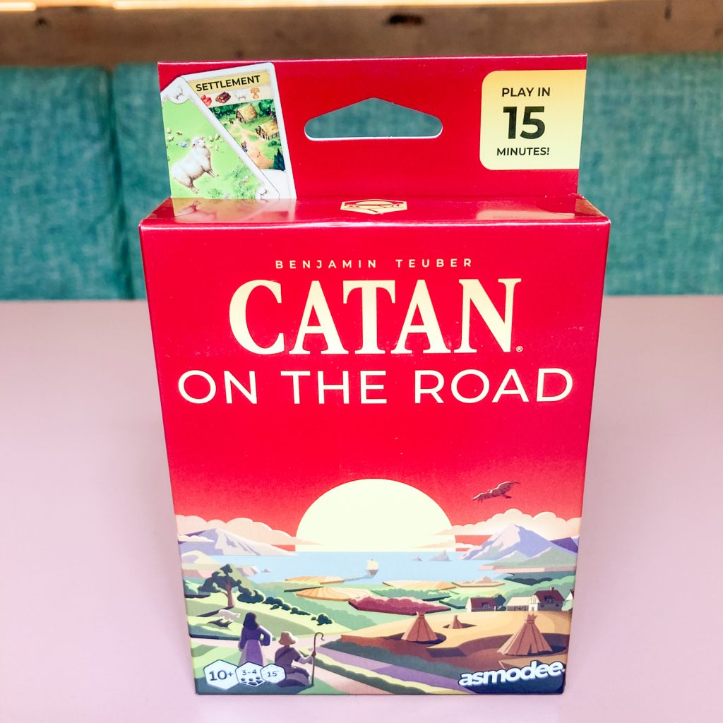 Red Catan: On the Road game box with sunset landscape illustration and 'Play in 15 minutes' label where visible.