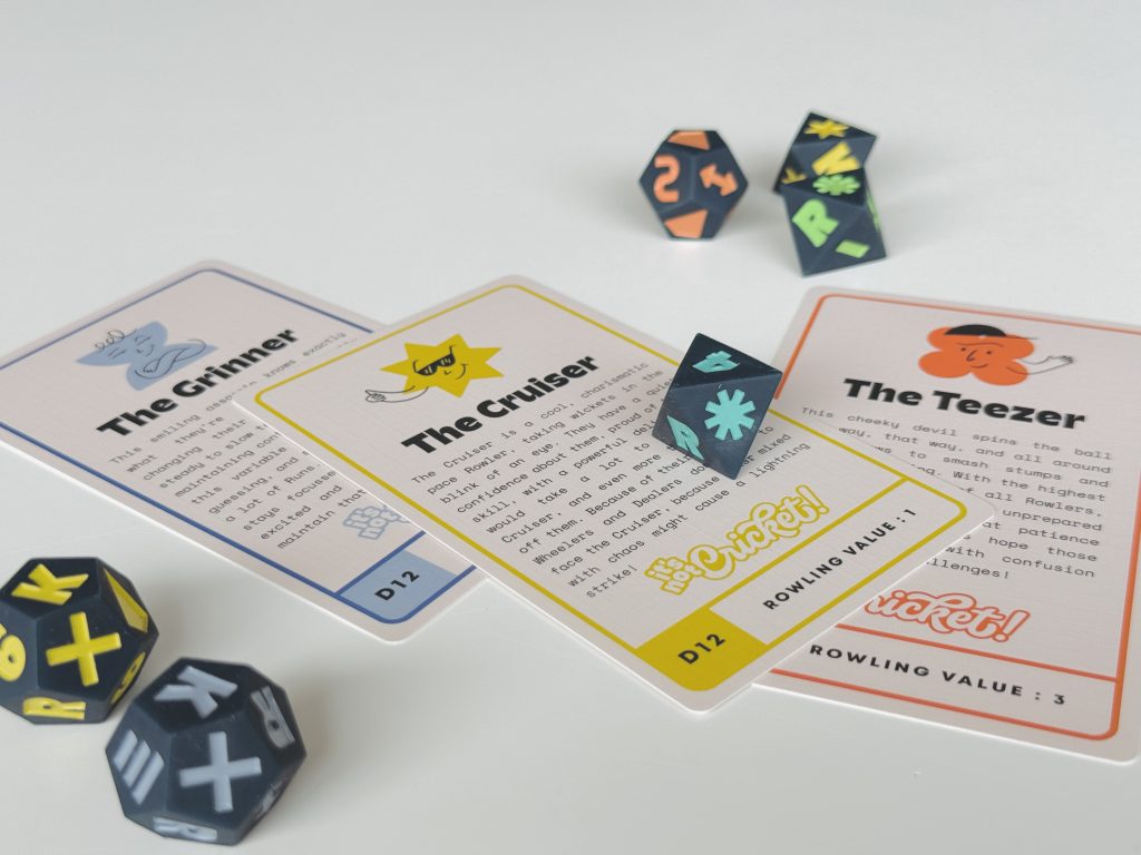 IMG_2184 - Chance & Counters Close-up of blue polyhedral dice with bright yellow letters and several illustrated story cards spread on a white table surface, ready for play.