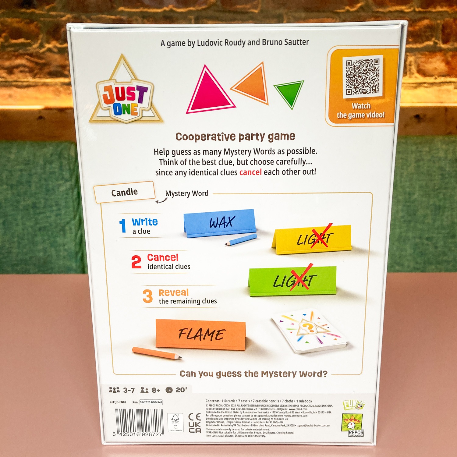 JUST_ONE_BACK - Chance & Counters Box cover for a cooperative party game featuring three colorful triangles, the Just One logo, and instructions on guessing a Mystery Word.