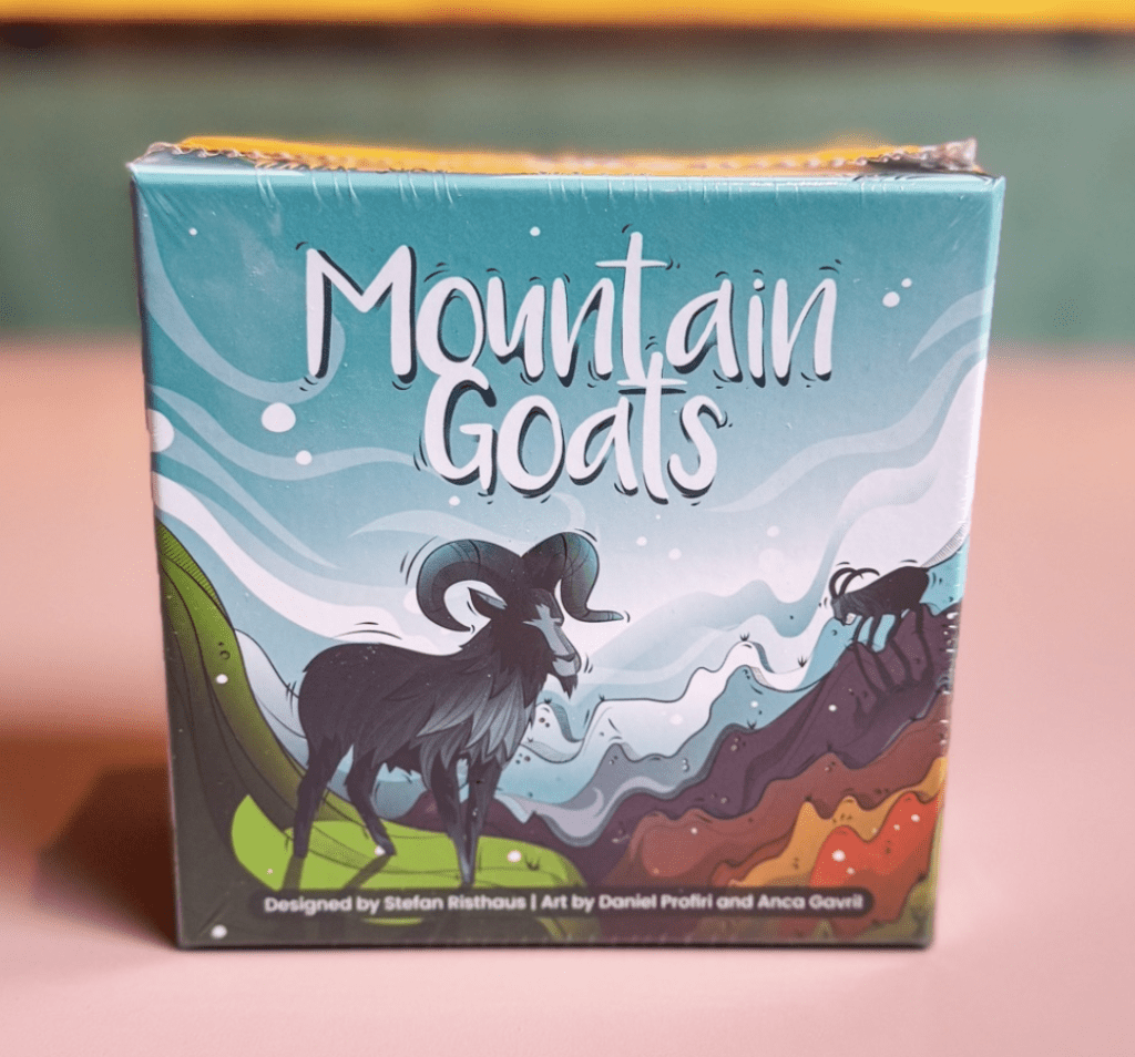 Box for the game Mountain Goats, featuring a black mountain goat against a blue, wavy mountain landscape and bold white title.