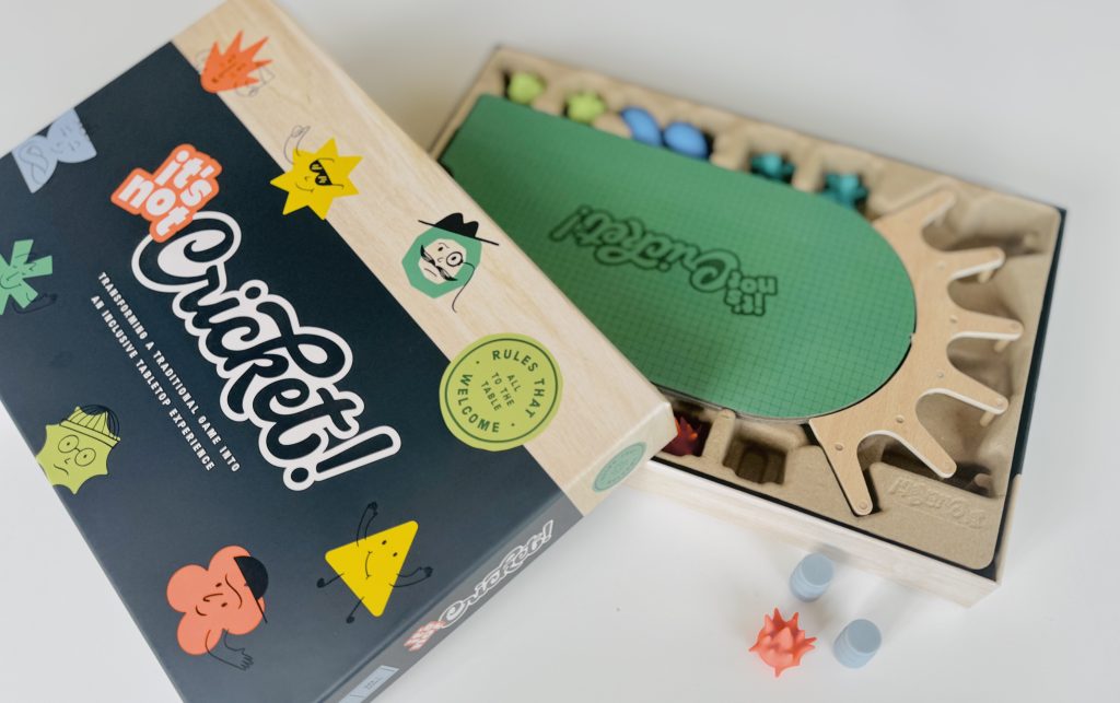 box pic - Chance & Counters Boxed board game with colorful stickers and a green game board partially visible, plus wooden tray with plastic game pieces and small tokens nearby.